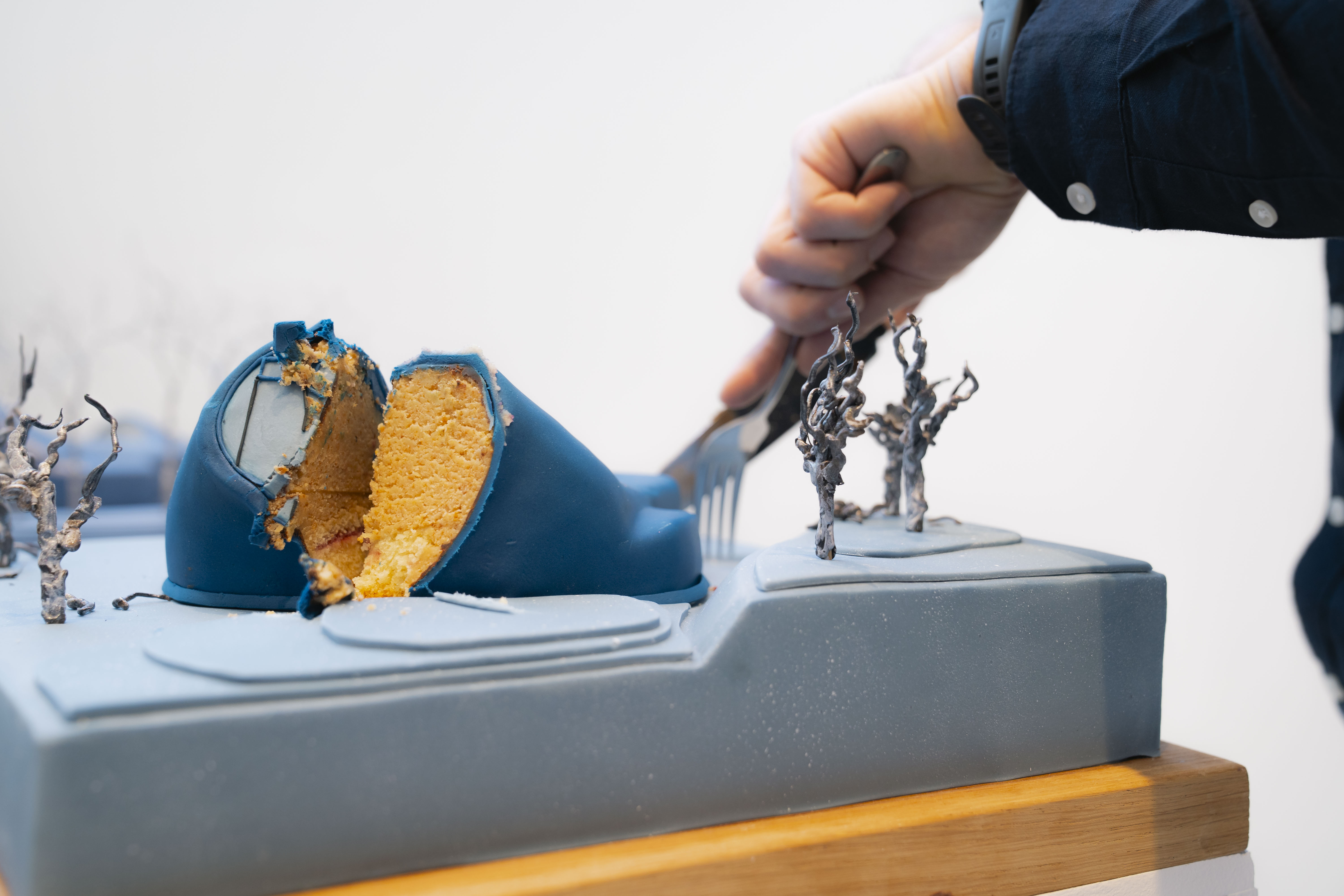 Hand with a knife cutting into realistic blue model of the Drawing Studio, only to reveal it was cake all along. Yum.