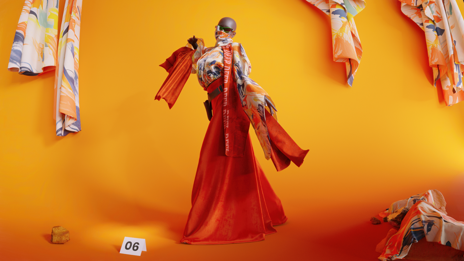 A model wearing primarily orange and patterned clothing faces away from the camera towards a yellow-orange background, with a few sheets of fabric on the wall behind them.