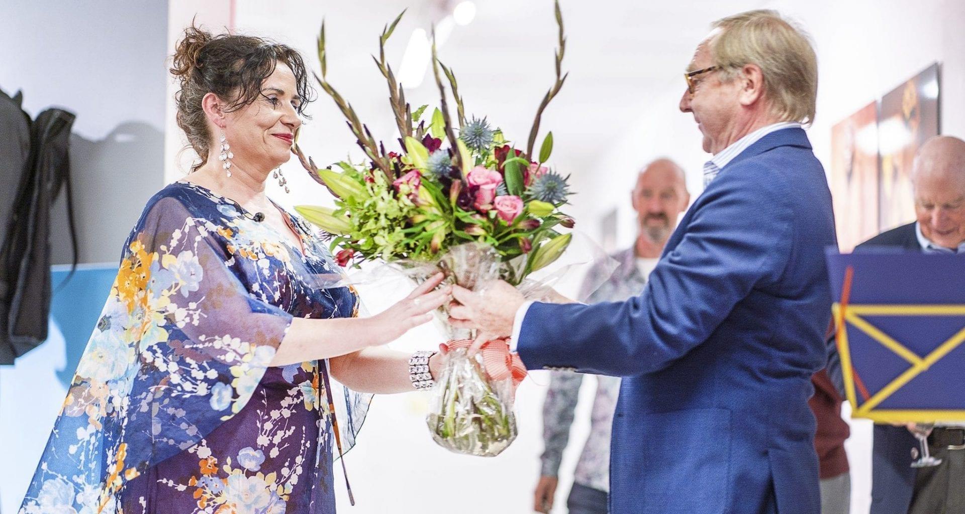 A man presents a large bouquet of flowers to a woman.
