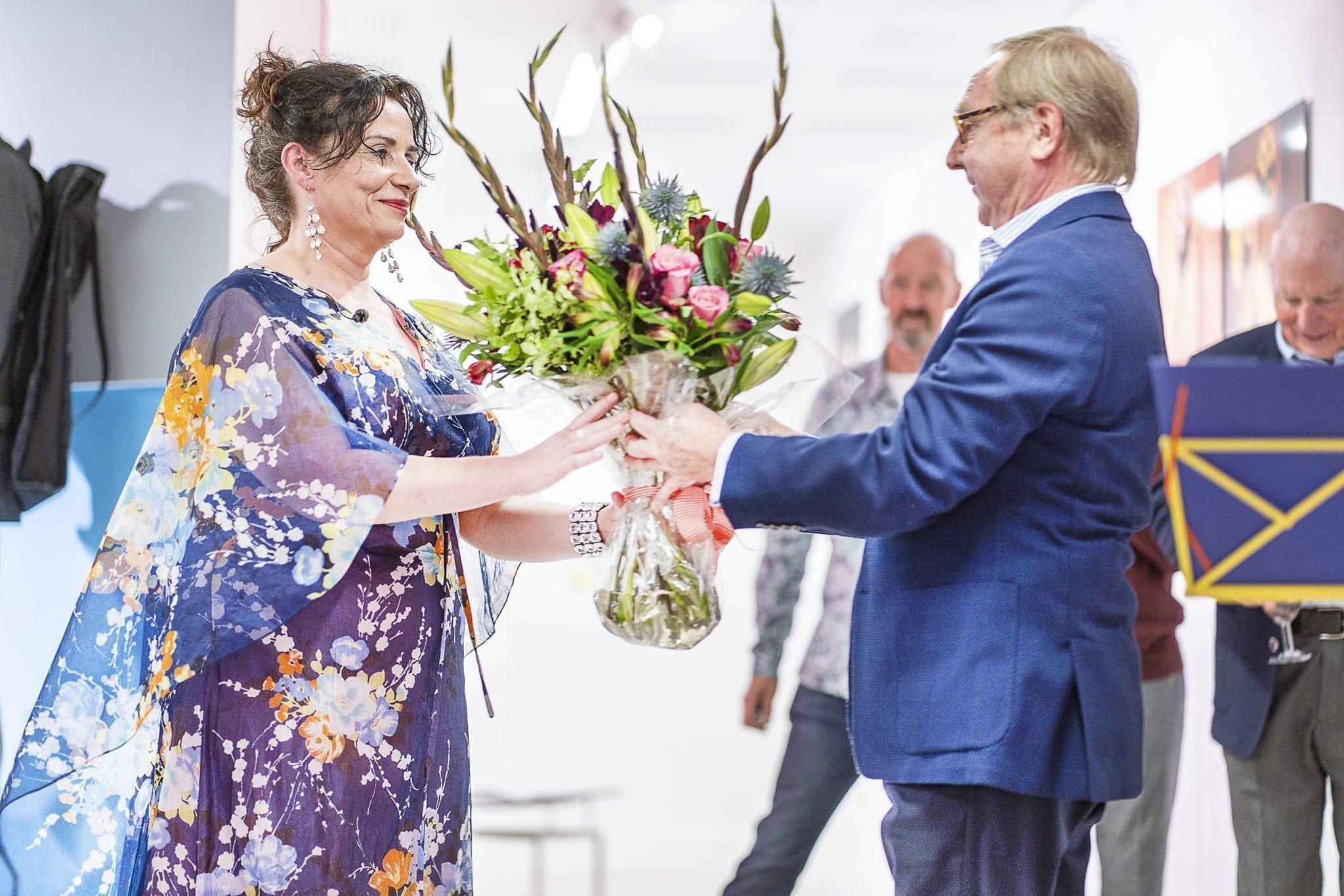 A man presents a large bouquet of flowers to a woman.