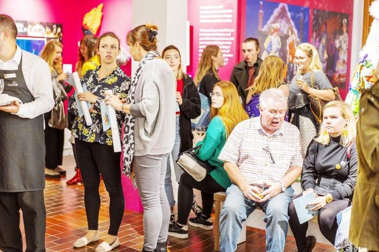 A crowd of people attending an event at a gallery.