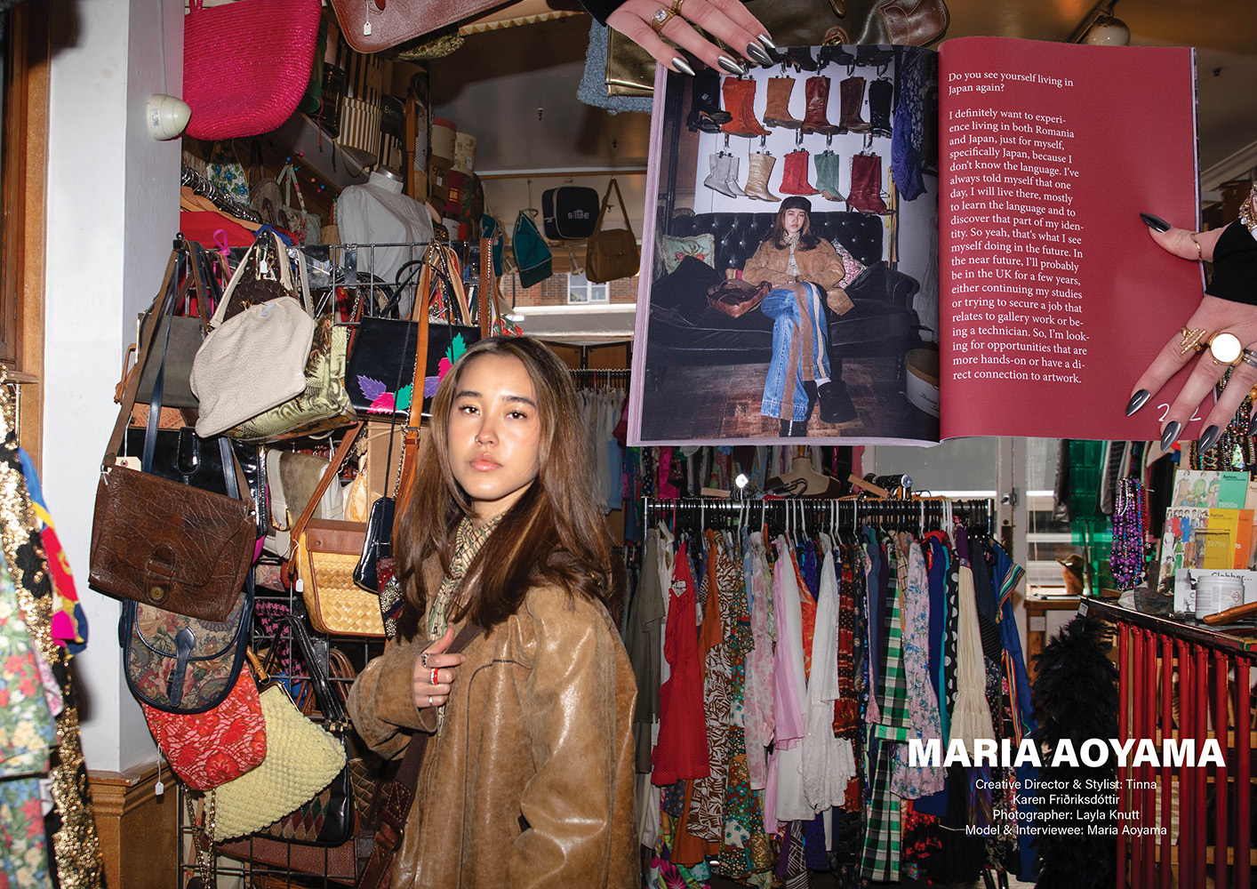 Woman in brown leather jacket standing in cluttered vintage shop with hanging bags, clothing racks, and red signage on walls.