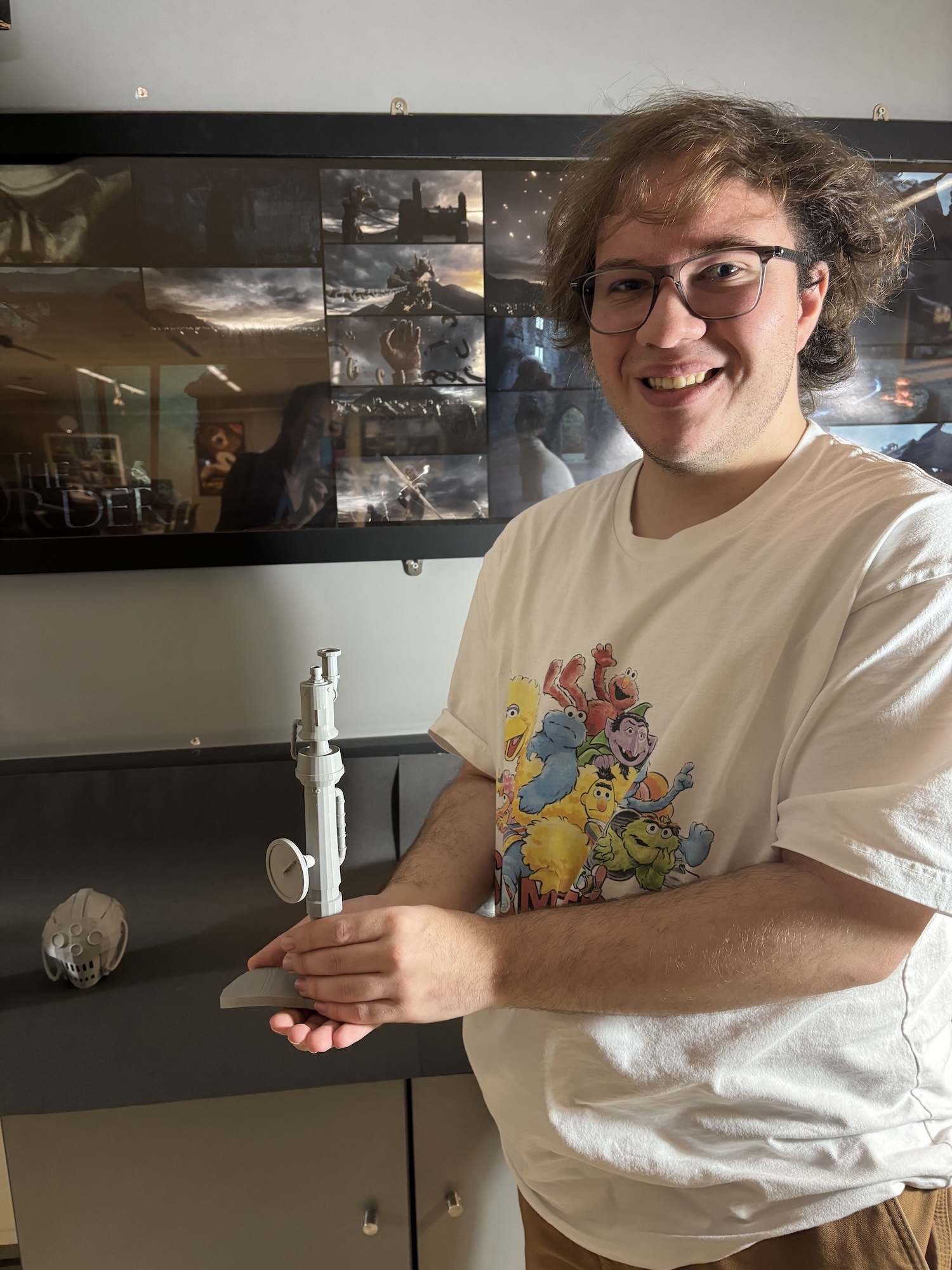 BA (Hons) Games Art and Design student standing and holding a 3D printed model of a steampunk-style whisk.