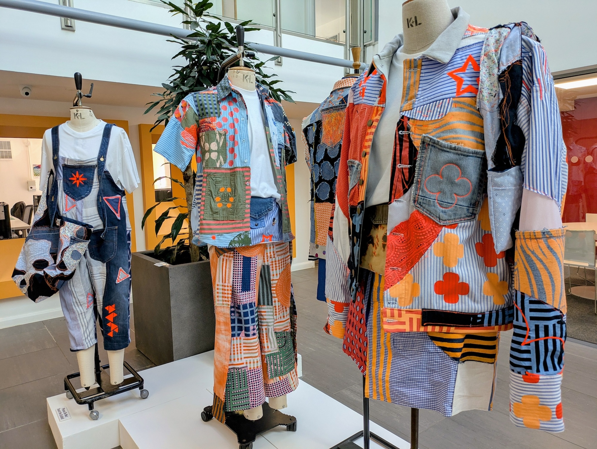 Three mannequins dressed with different, colourful patchwork-style outfits, displayed in University House, Arts University Bournemouth.
