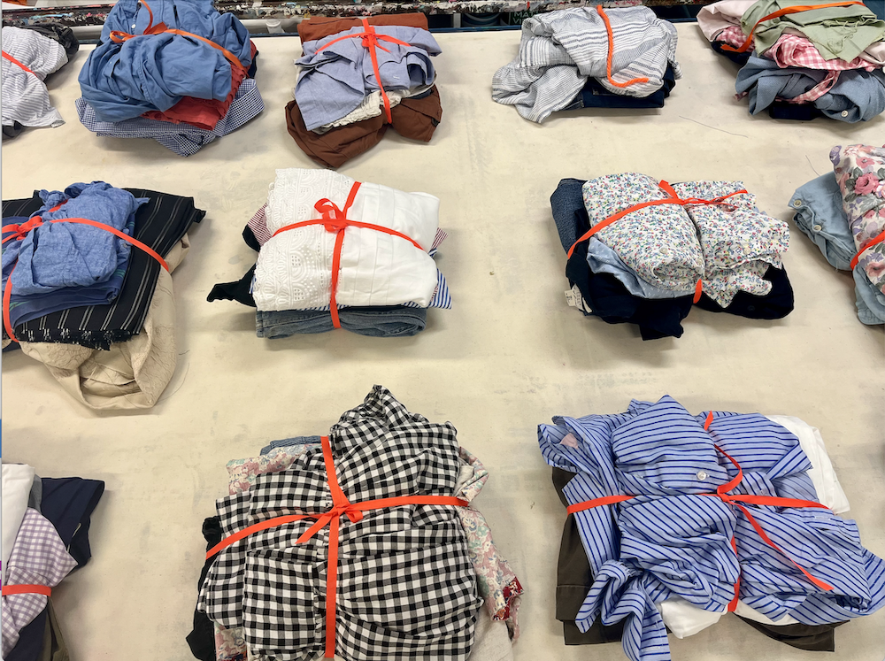 Several bundles of clothes lying folded and tied with red string on a white surface.