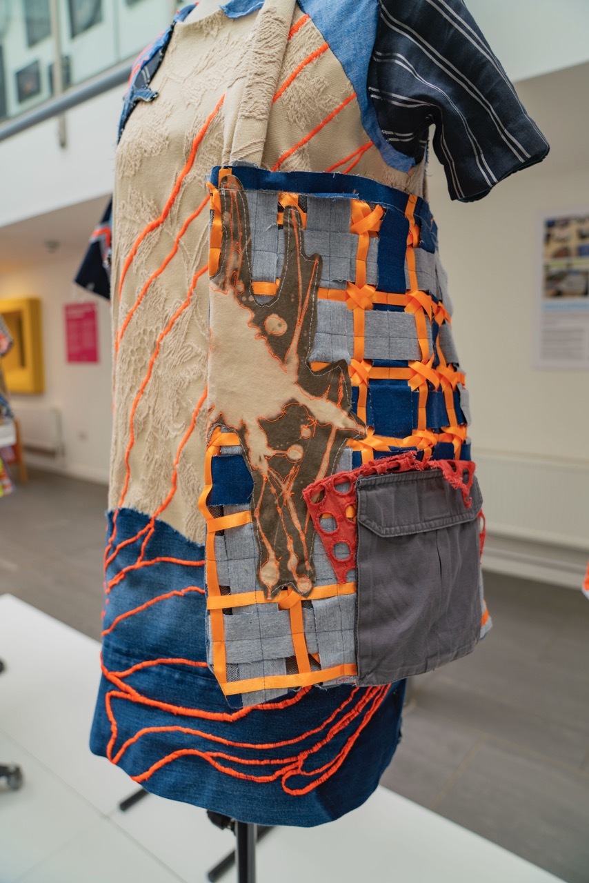 Close-up on Trash to Treasure clothing piece, with blue, orange and red textile patchwork.