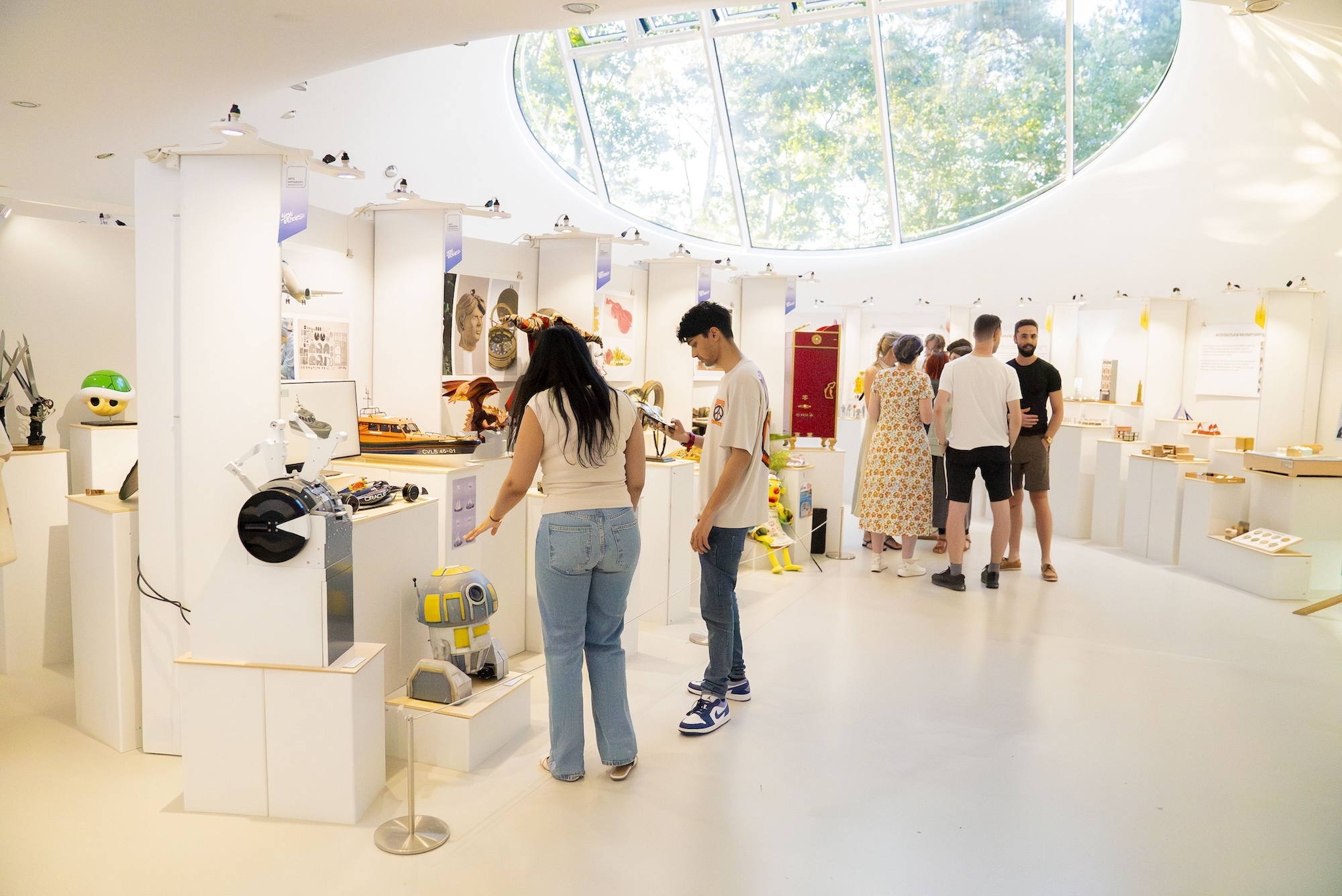 Several people exploring a BA (Hons) Modelmaking exhibition at the Drawing Studio at AUB during the 2024 Summer Shows.