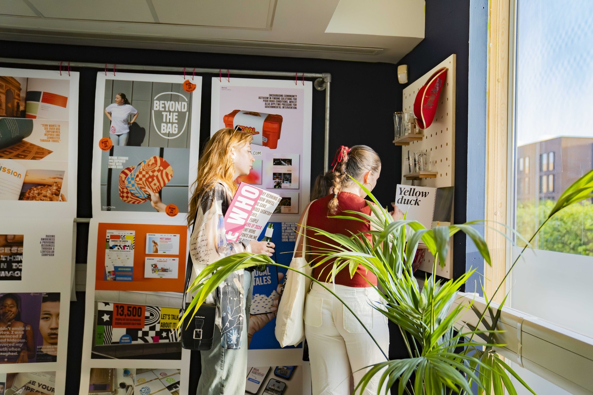 Two people looking at a BA (Hons) Graphic Design display at the 2024 Undergraduate Summer Shows at Arts University Bournemouth.