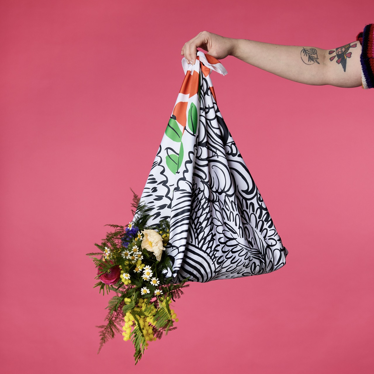 Multicoloured, pattered Lush Knot Wrap on a bright coral pink/red background.