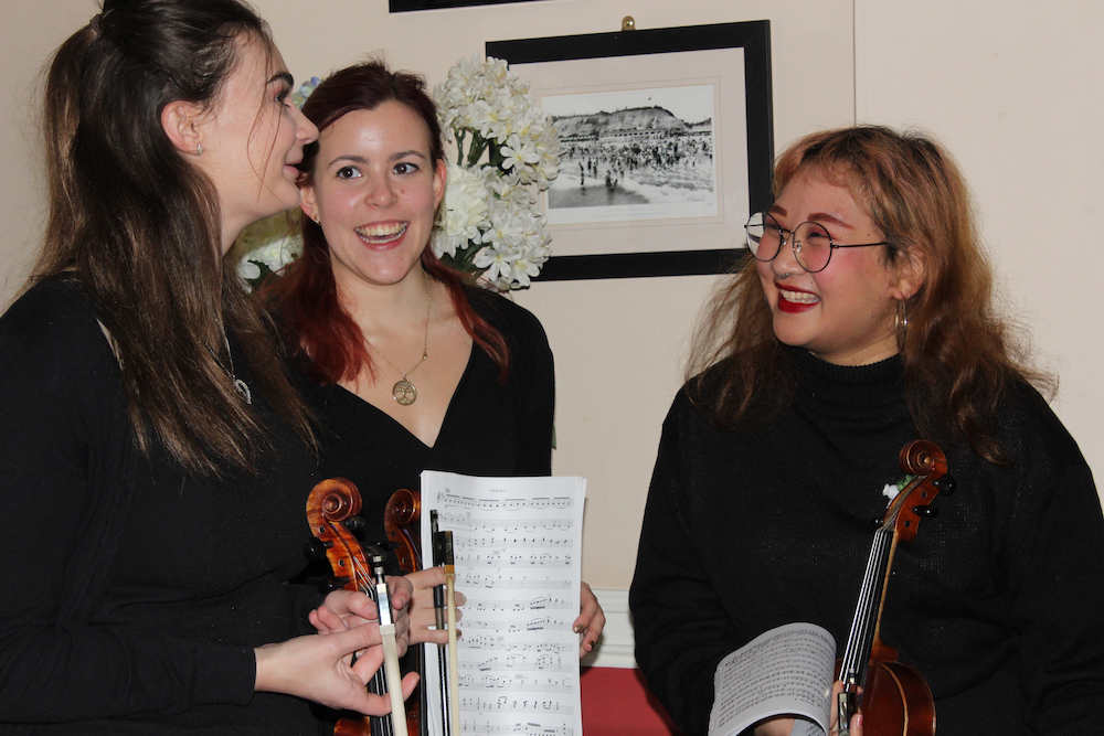 Students discussing University Music whilst holding a music sheet