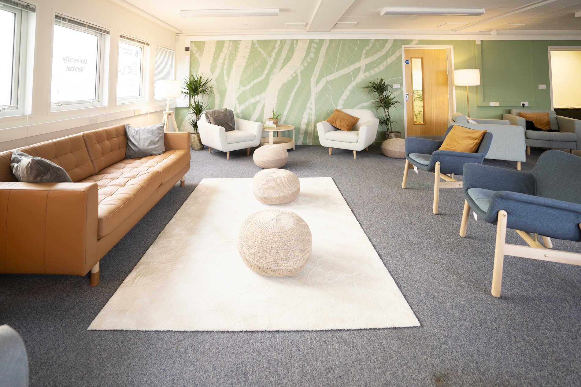 Three beanbag stools resting on a white rug, with sofas and armchairs set up around it.