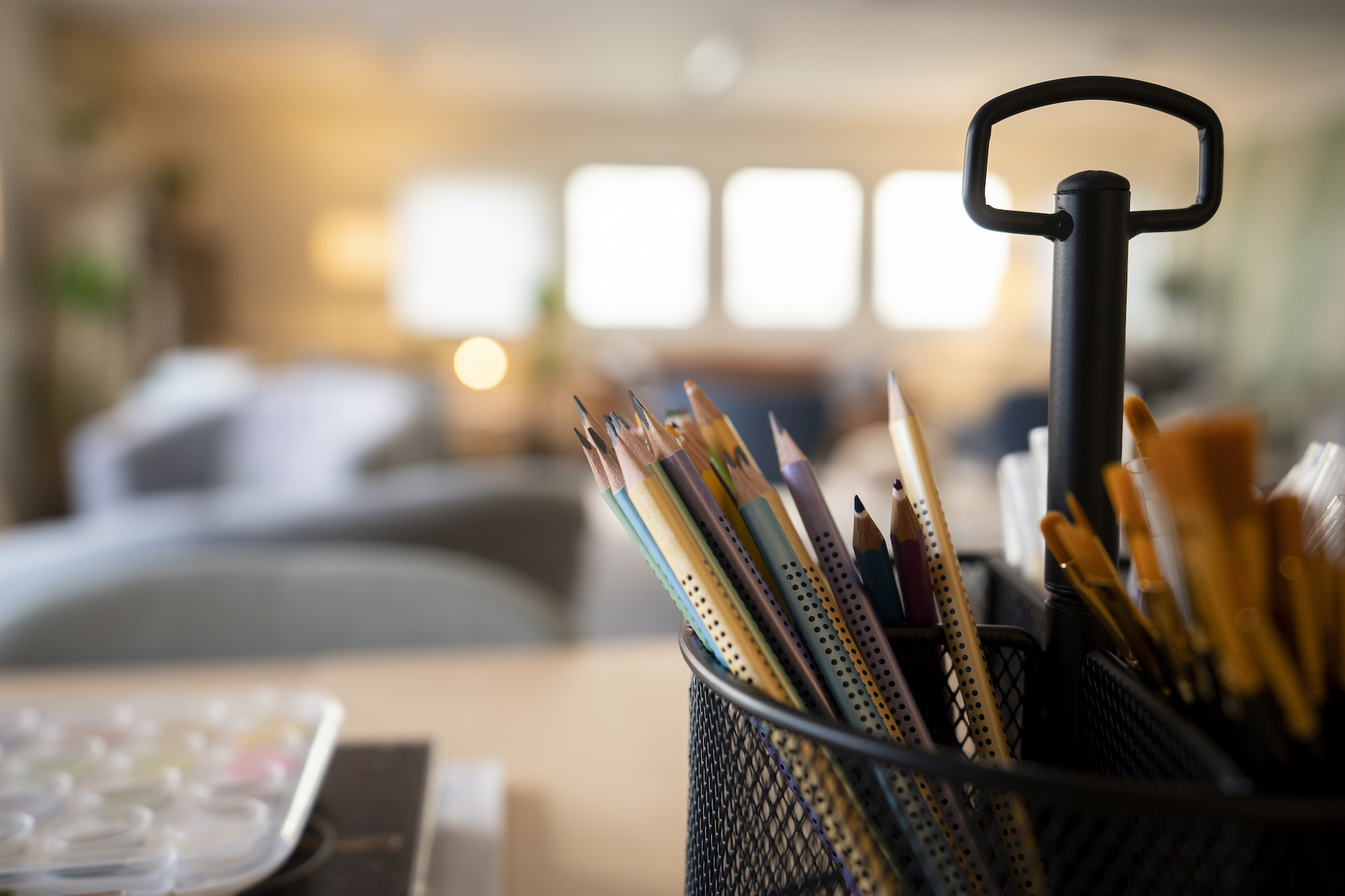 Close-up of coloured pencils in a pencil holder, sitting on a table.