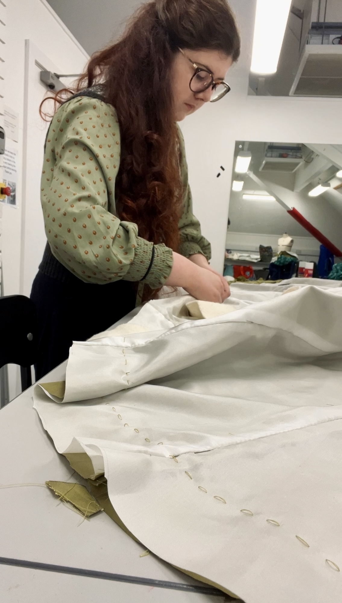 MA Historical Costume student V Joy standing at a work station at Arts University Bournemouth working on a length of material.