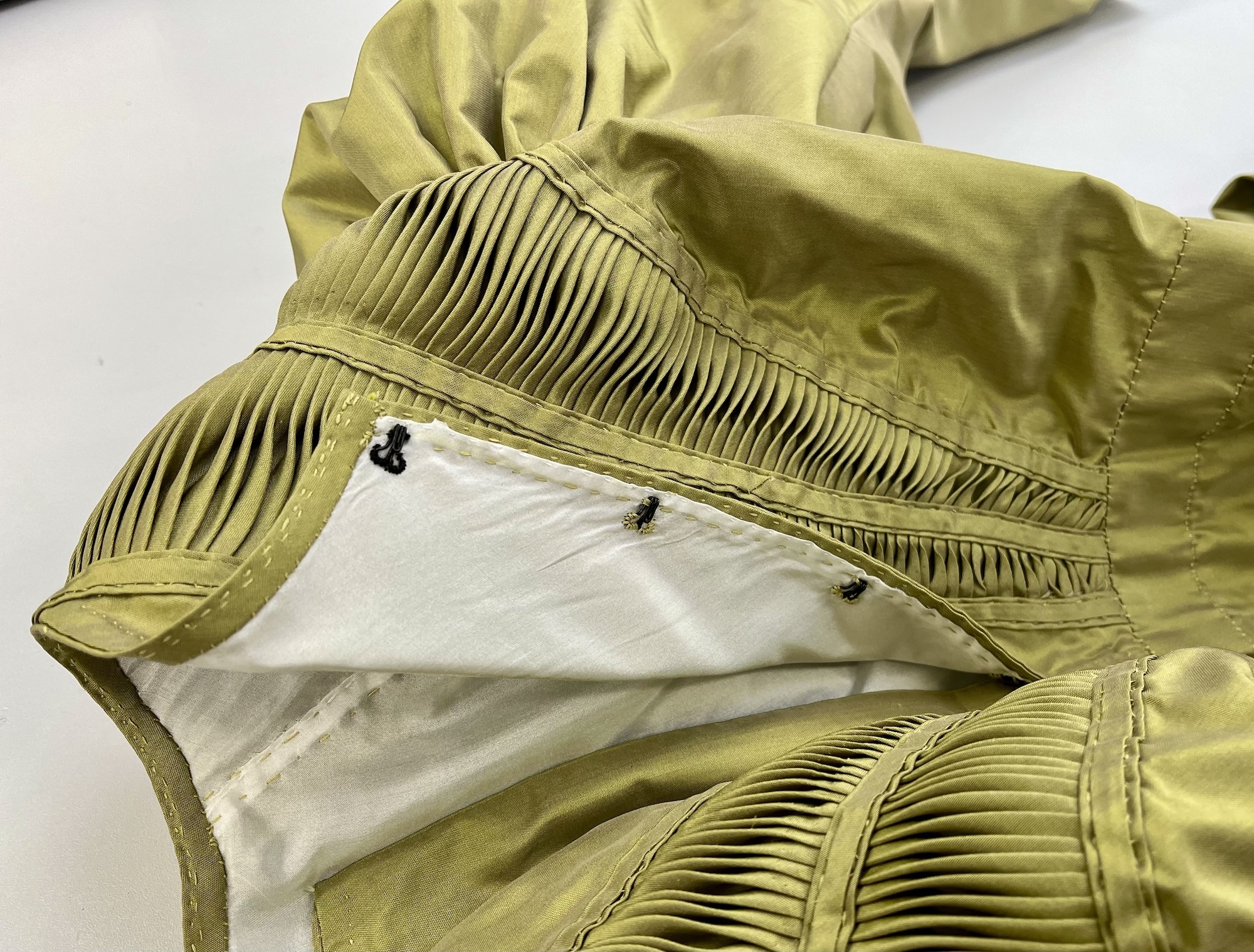 Close-up of part of the back panel of a green silk 19th century dress.