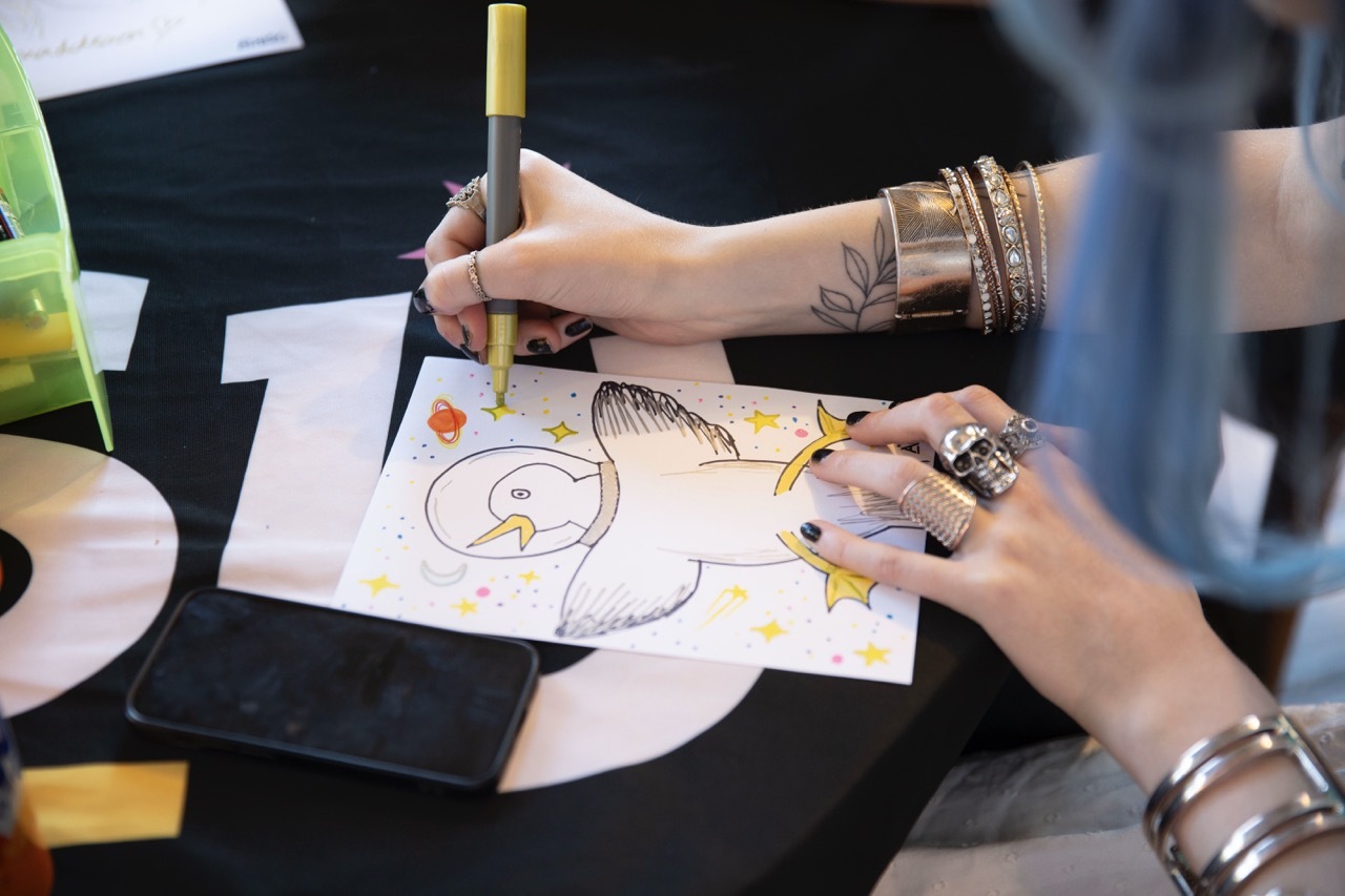 Person drawing a fun space-themed seagull with yellow stars.
