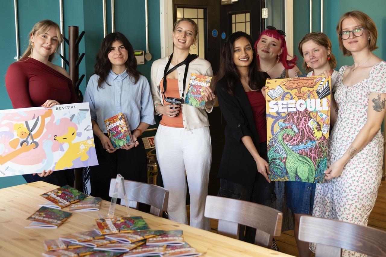 The student team behind Seegull posing with posters and copies with illustrations of the front cover. Maria Bishop is stood on the far right.