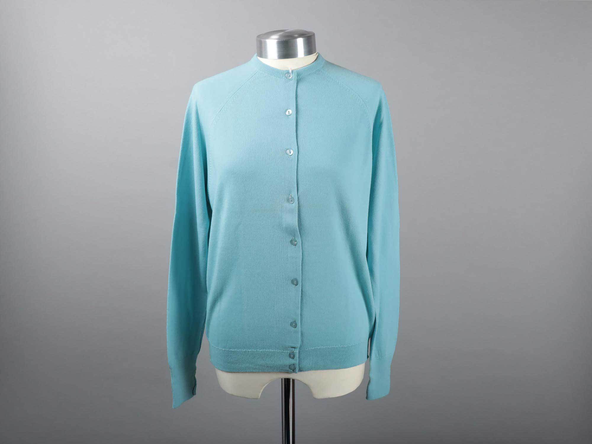 A blue synthetic cardigan hanging on a mannequin.