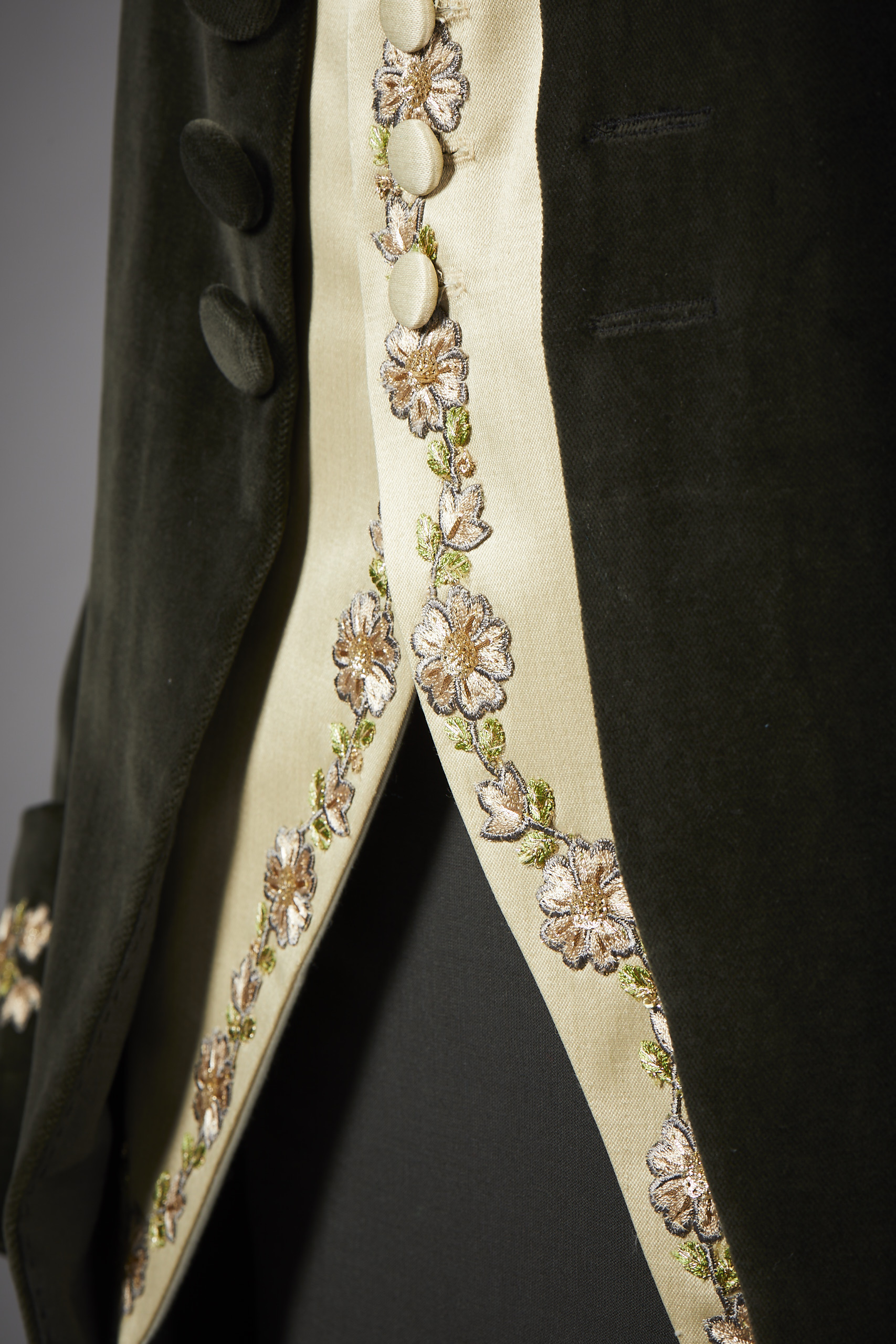 Close-up of a gold waistcoat and a dark-coloured frock coat over it.