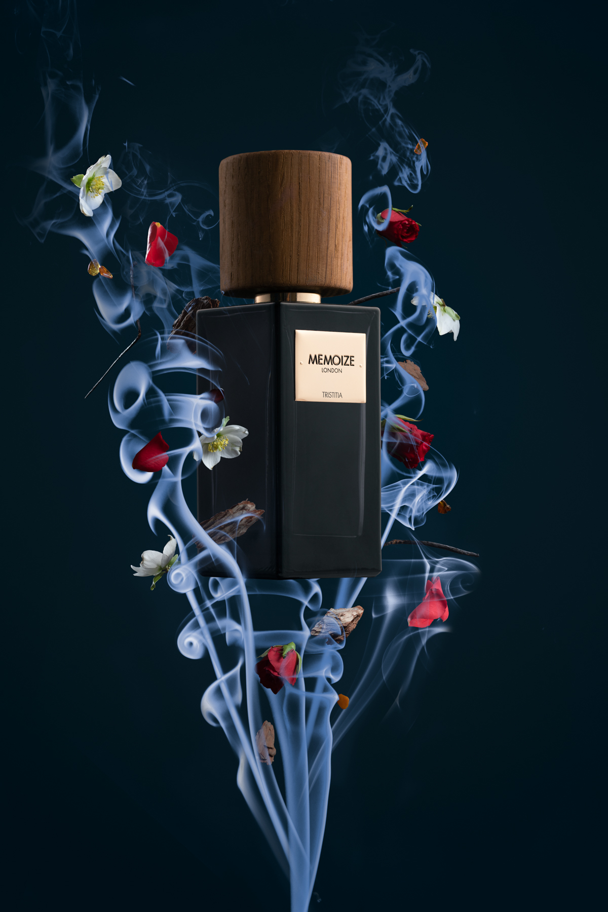 A bottle for a perfume called "Memoize" surrounded by smoke and flower petals.