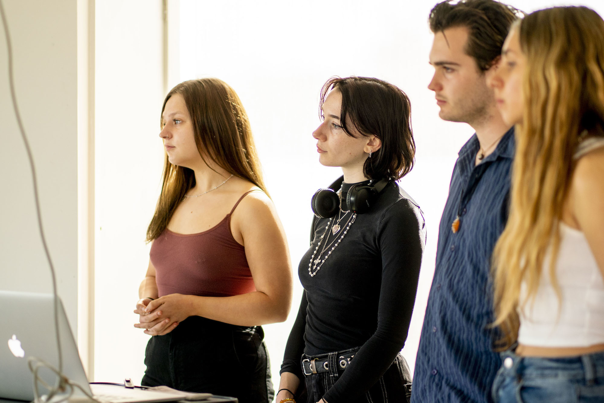 Four Arts University Bournemouth students standing by a laptop while giving a presentation.