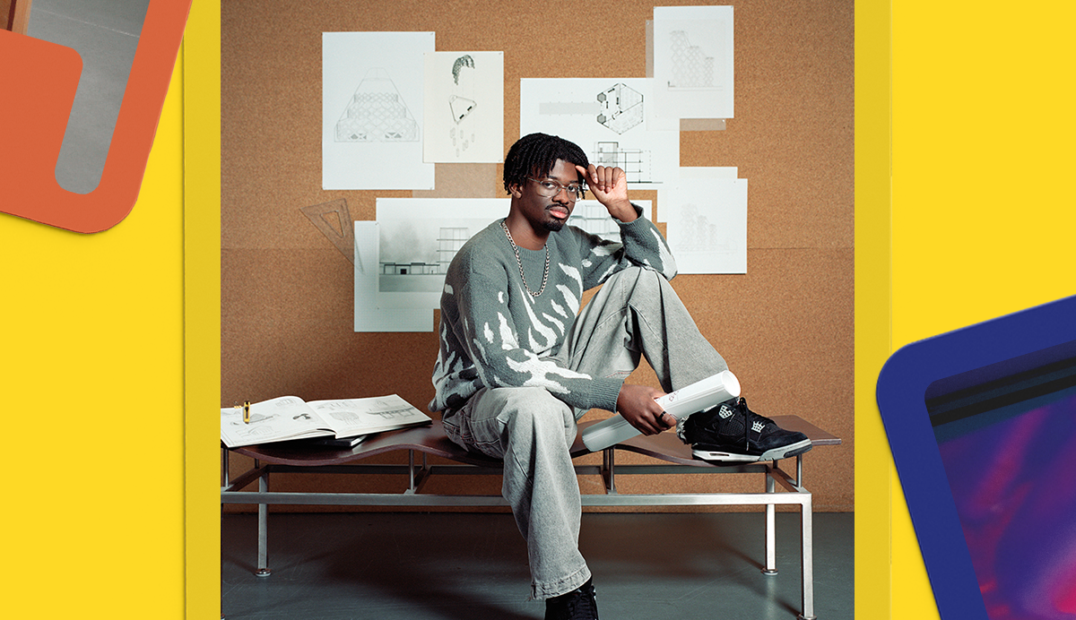 Man in grey tracksuit sits on white bench, hand to head. White papers on brown wall behind. Yellow and orange painted walls.