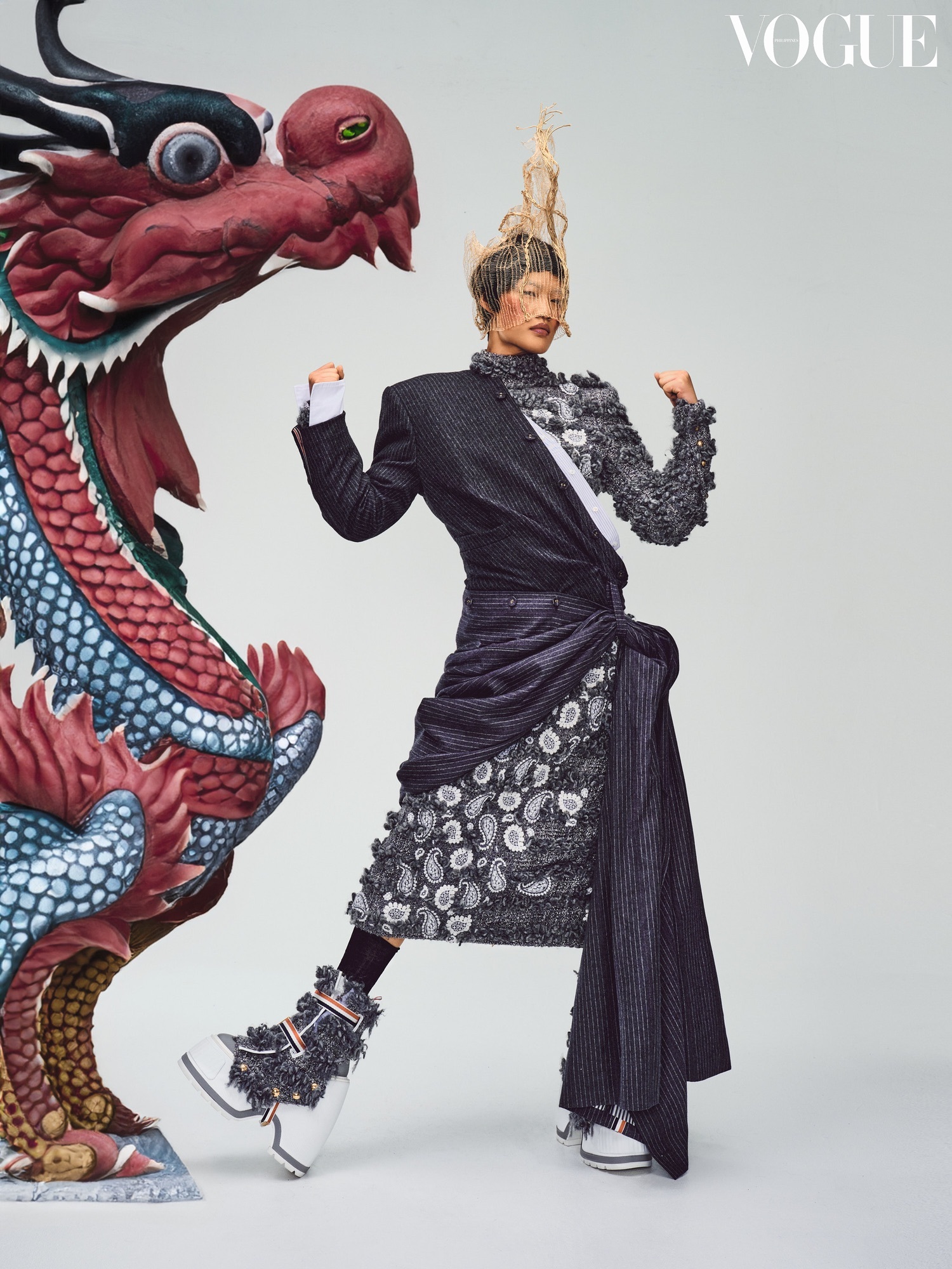 A woman in a black and white dress and gold headpiece, stood next to a large model of a red Chinese-style dragon.