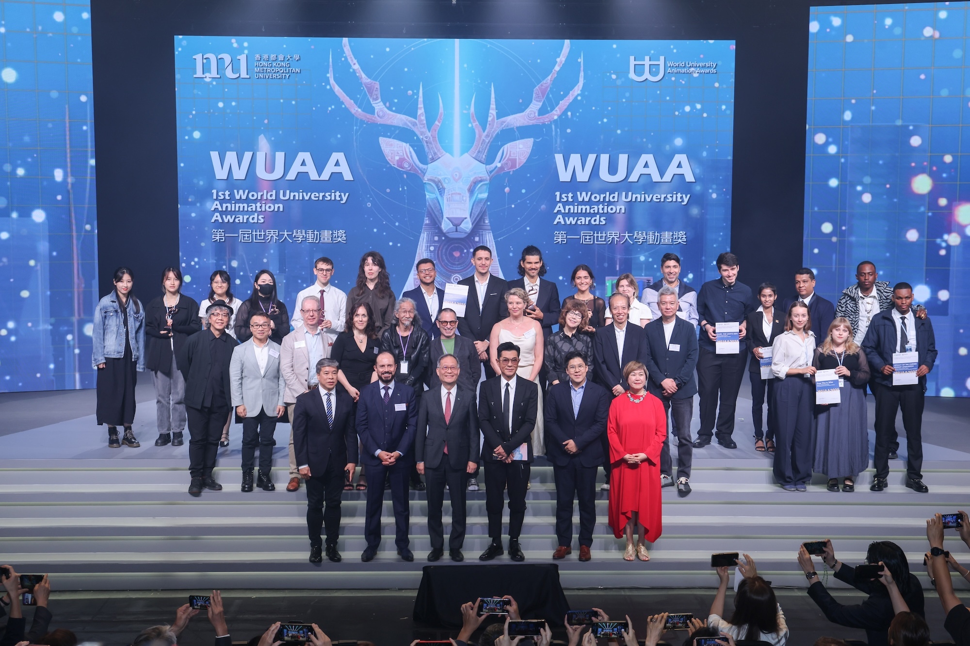 Group of formally dressed people on stage at WUAA event with blue backdrop featuring deer logo and Chinese text.