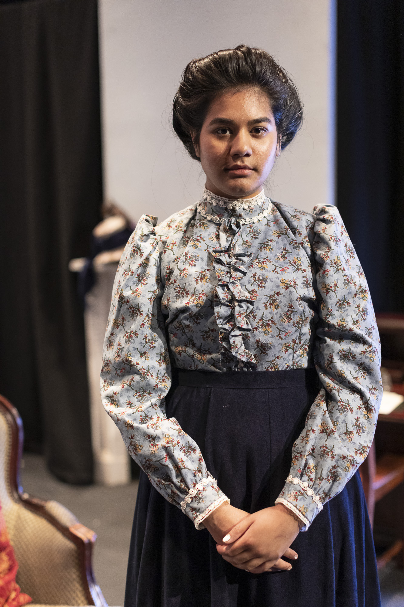 Close-up of an actor in a period costume: a blouse and skirt.