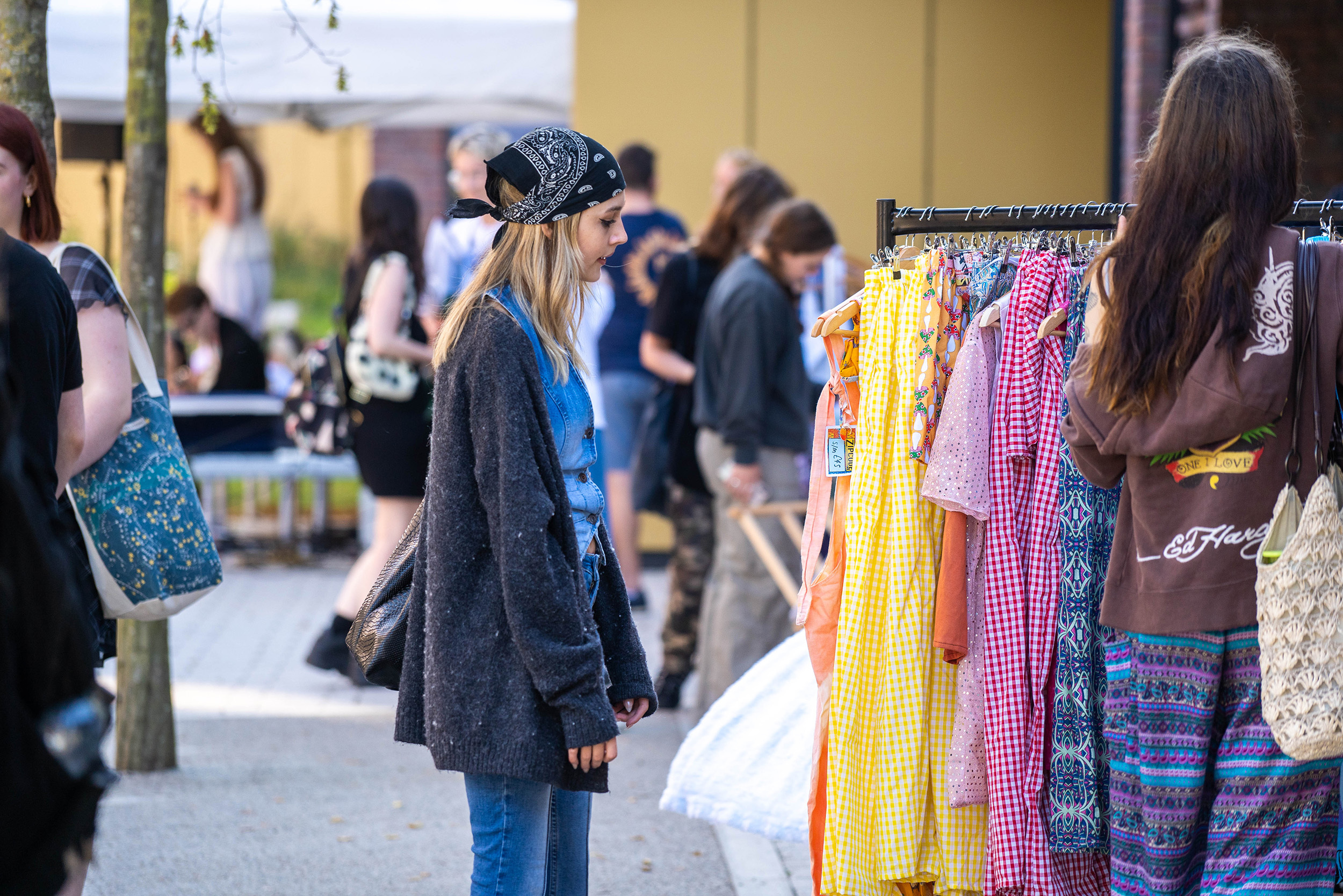 Students mingling outside a university building looking at market stalls