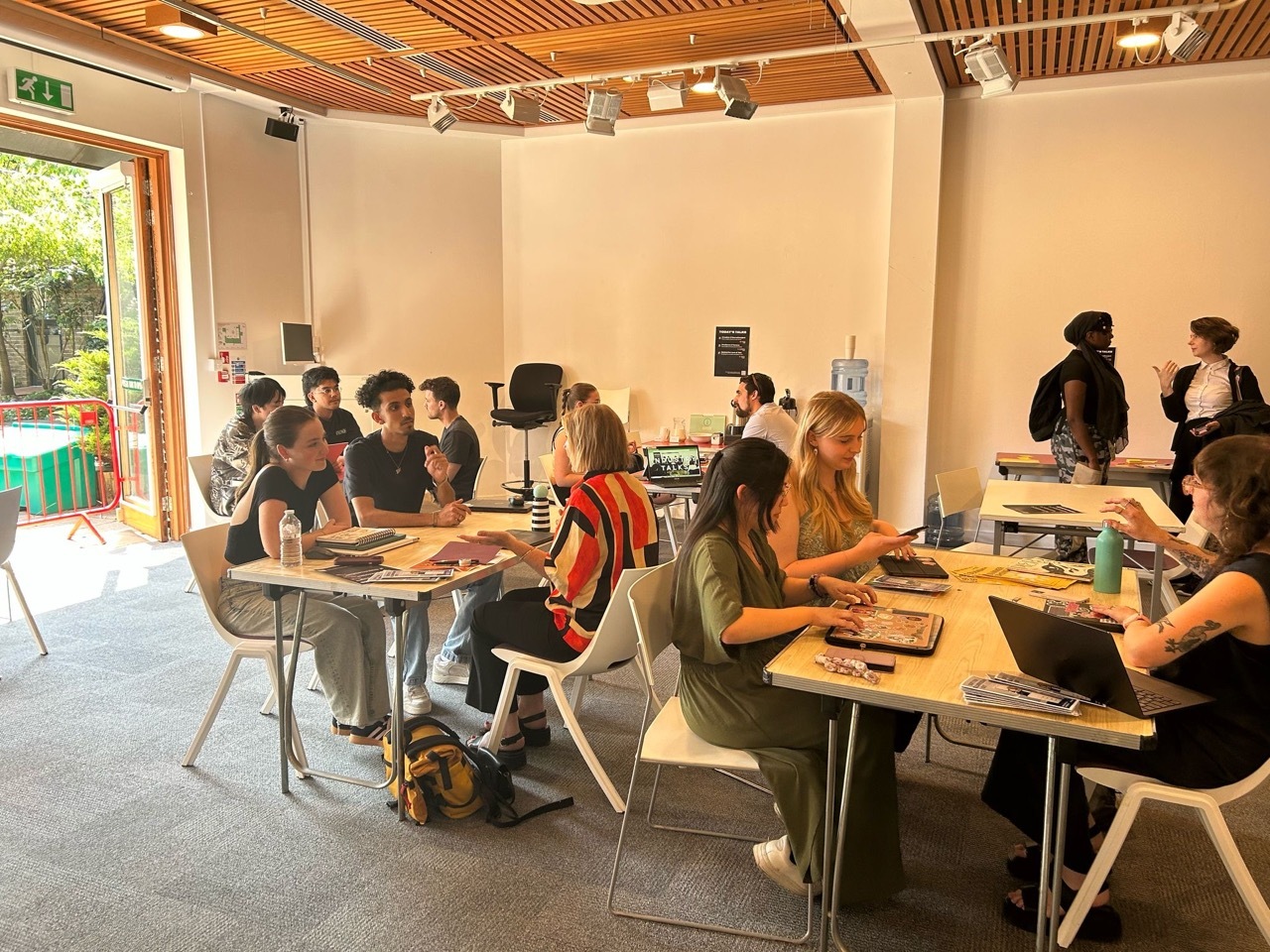 Students in a large sunny room talking to industry professionals on different tables.