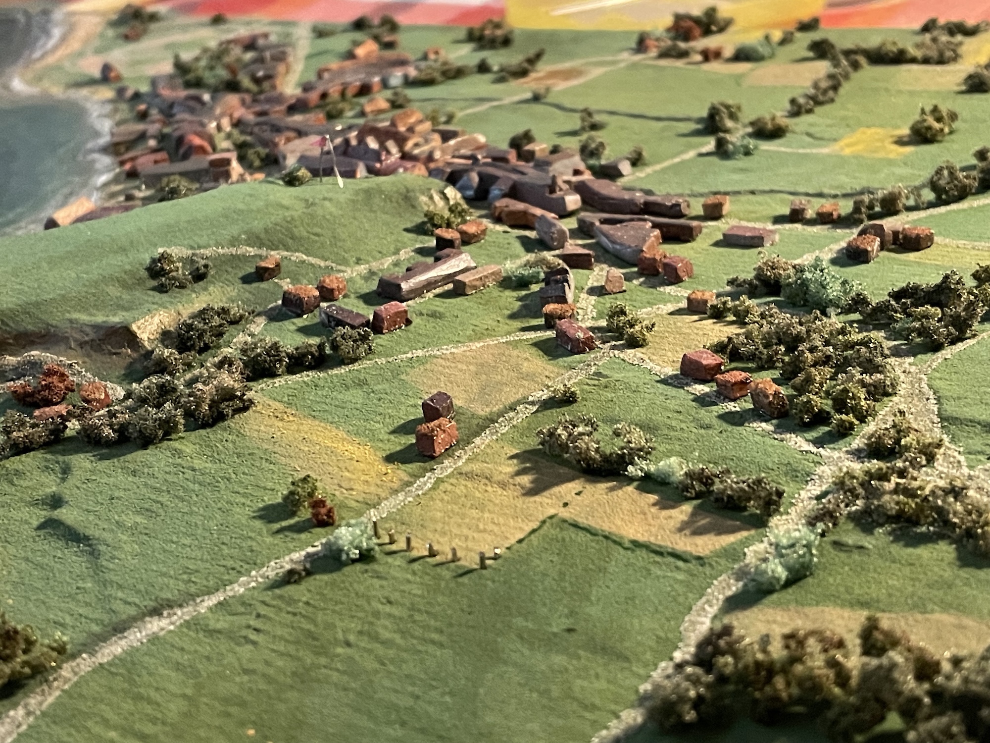 Diorama model of rolling green fields and villages in the distance.