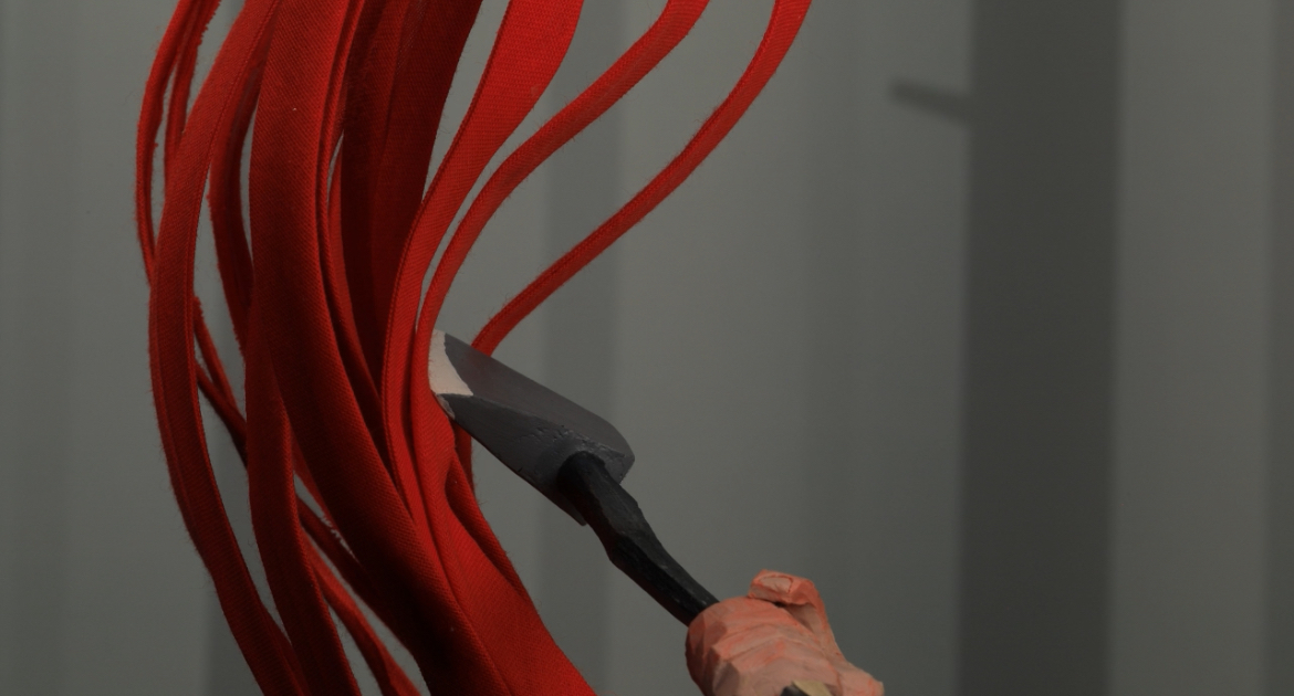Close-up of a pointed object being held up at a red vine-like object.