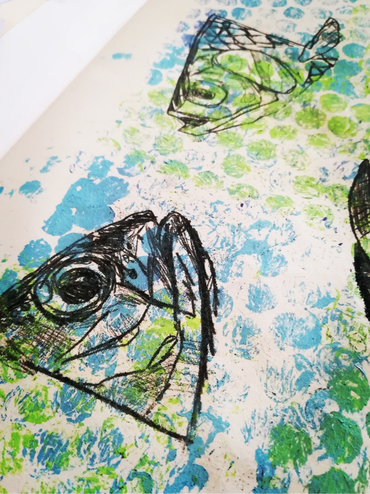 Page of a sketchbook with two sketches of fish heads facing each other, with fish scales printed in the background.