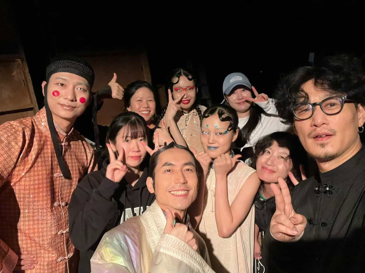 Group of people in theatrical costumes and makeup posing together, including traditional Japanese clothing and character face paint.
