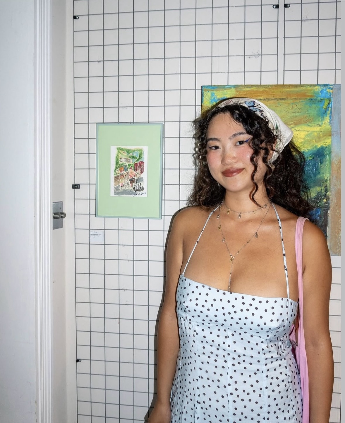 Portrait of an MA Illustration student next to a sample of her work displayed on a wall.