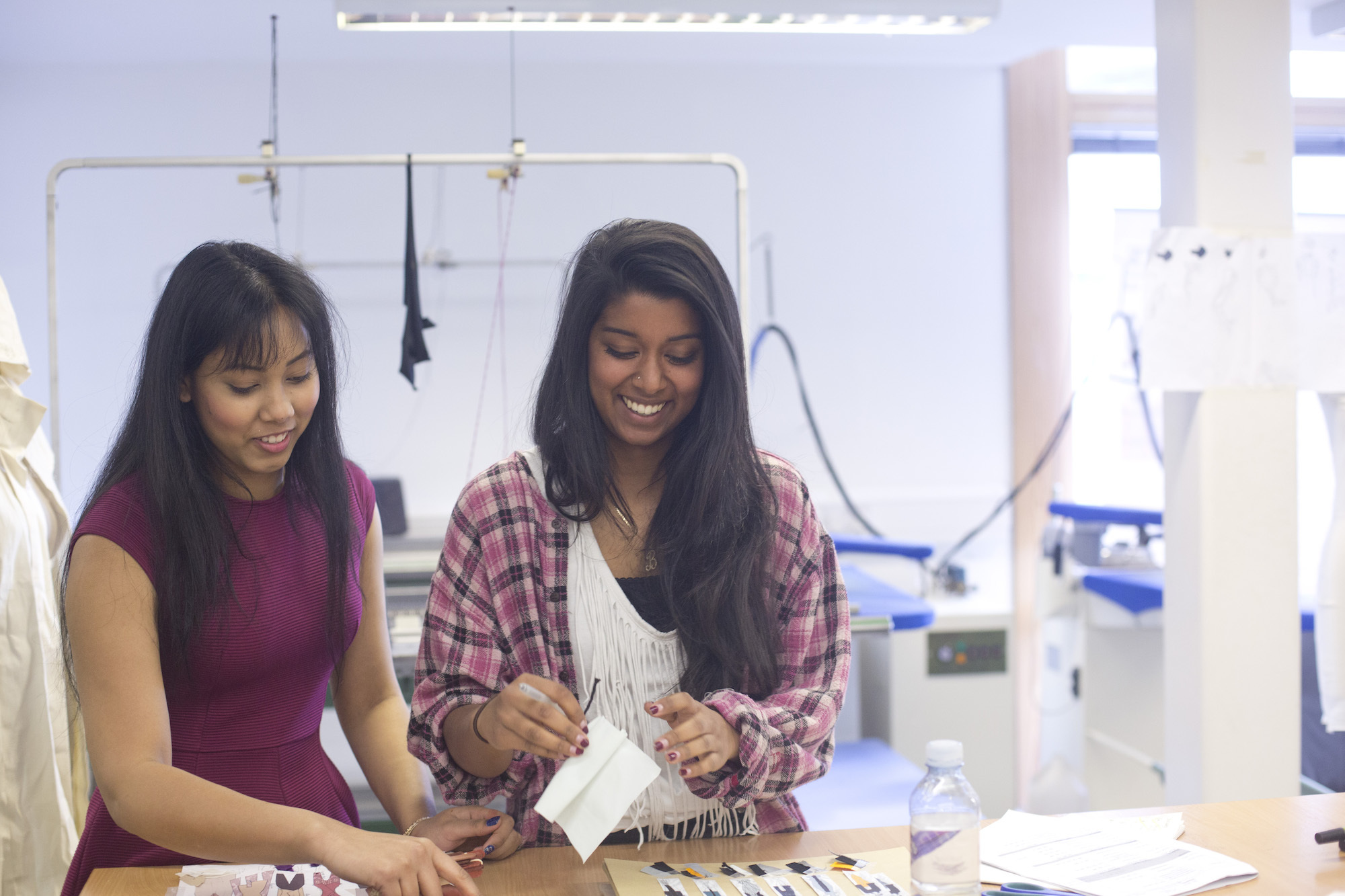 Two people standing by a table working with fabric samples in a studio.