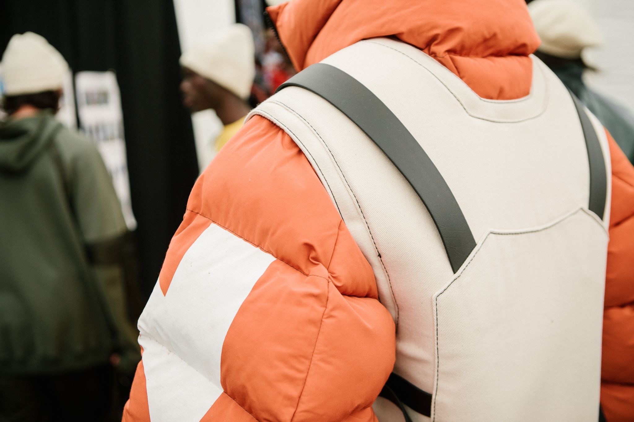 Person wearing orange high-visibility jacket with white reflective stripes and grey harness or safety equipment