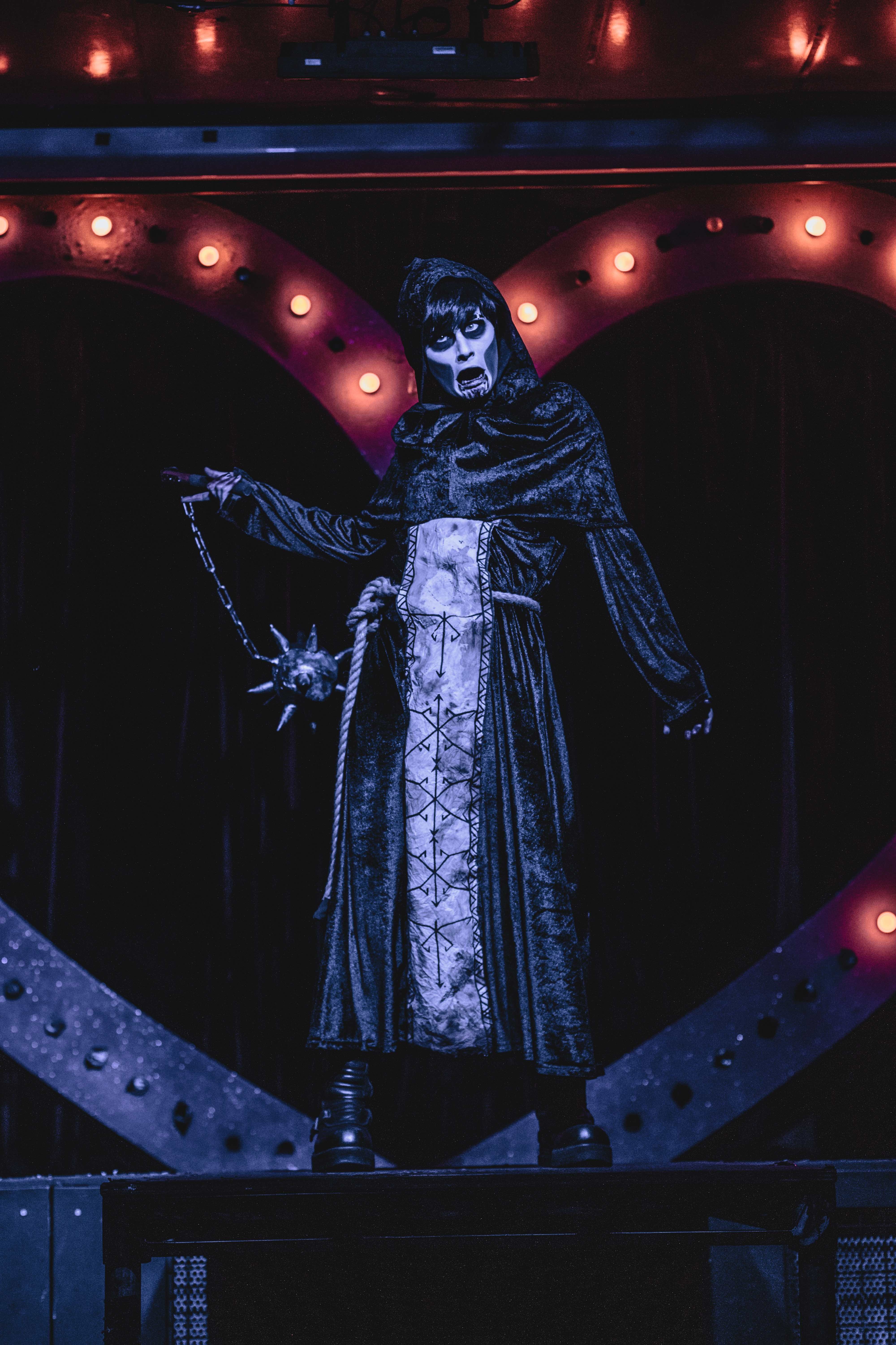 a person is dressed in a dark cloak. They are wielding a flail weapon.