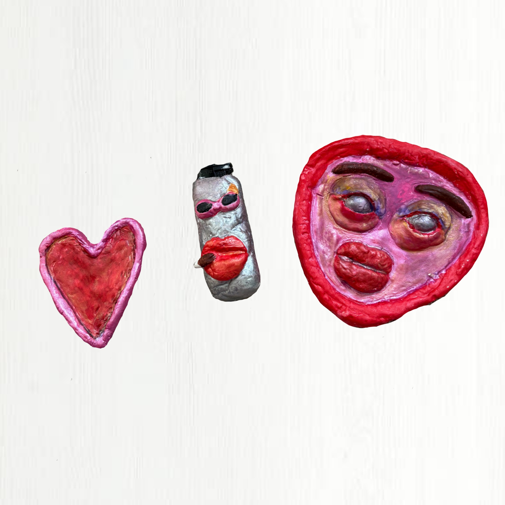 Three colourful clay figures on a white background: a pink love heart, a grey character with sunglasses and red lips, and a large pink face with prominent features including bold lips and eyes.