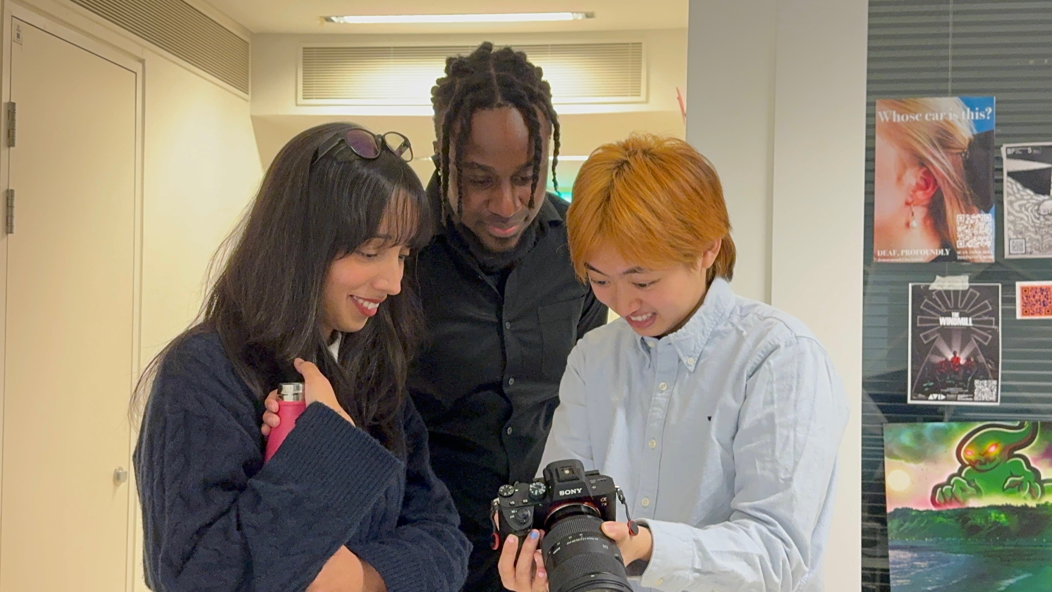 Three MA Film Practice students looking at an image on a camera.