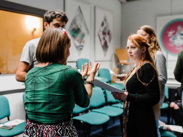 Three people rehearsing a play from a script.