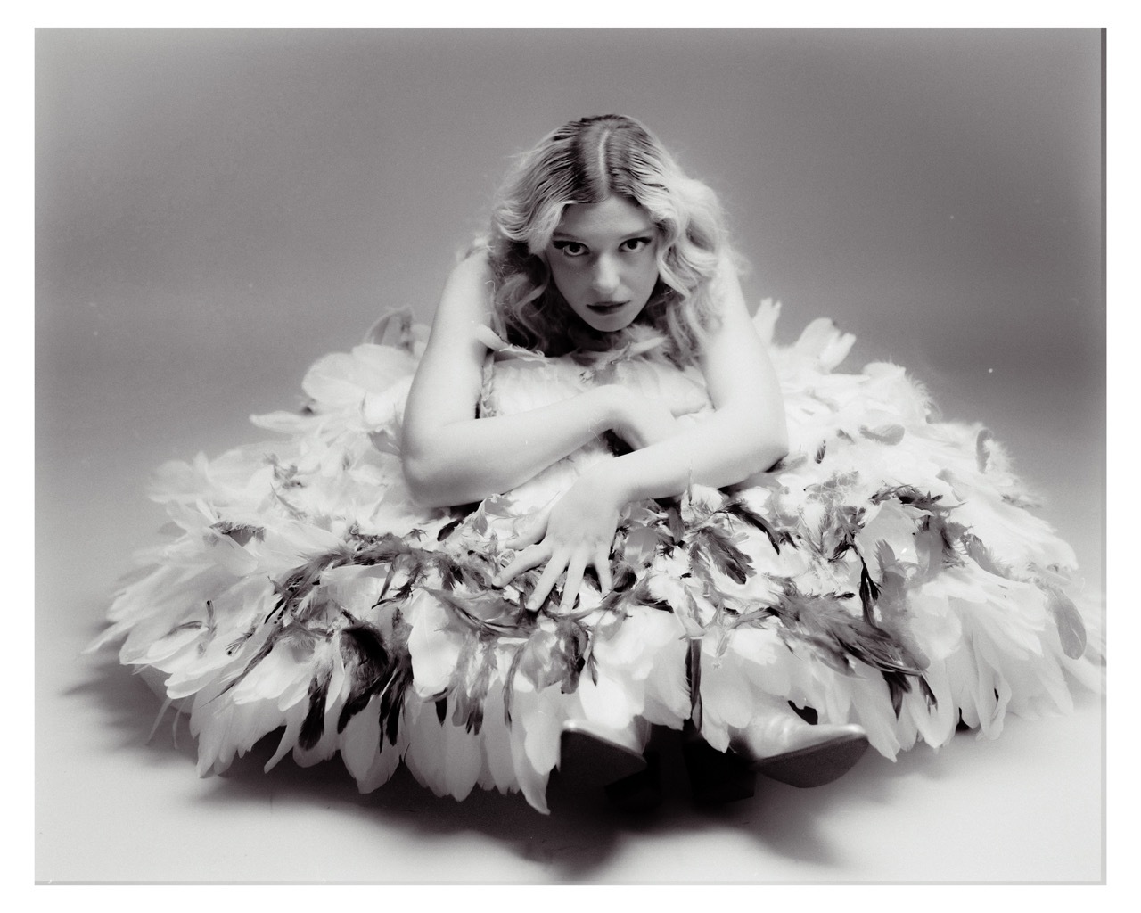 A model in a black-and-white flm photo wearing a feathered dress.