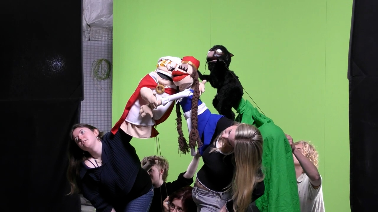 BA (Hons) Modelmaking students holding assorted puppets and performing in front of a greenscreen in a studio at Arts University Bournemouth.