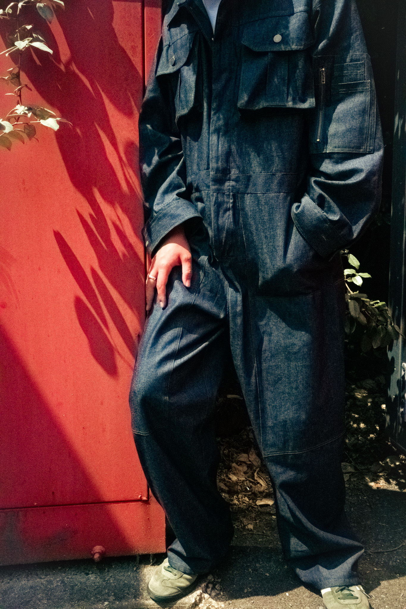 A person dressed in a blue work-suit in front of a red background
