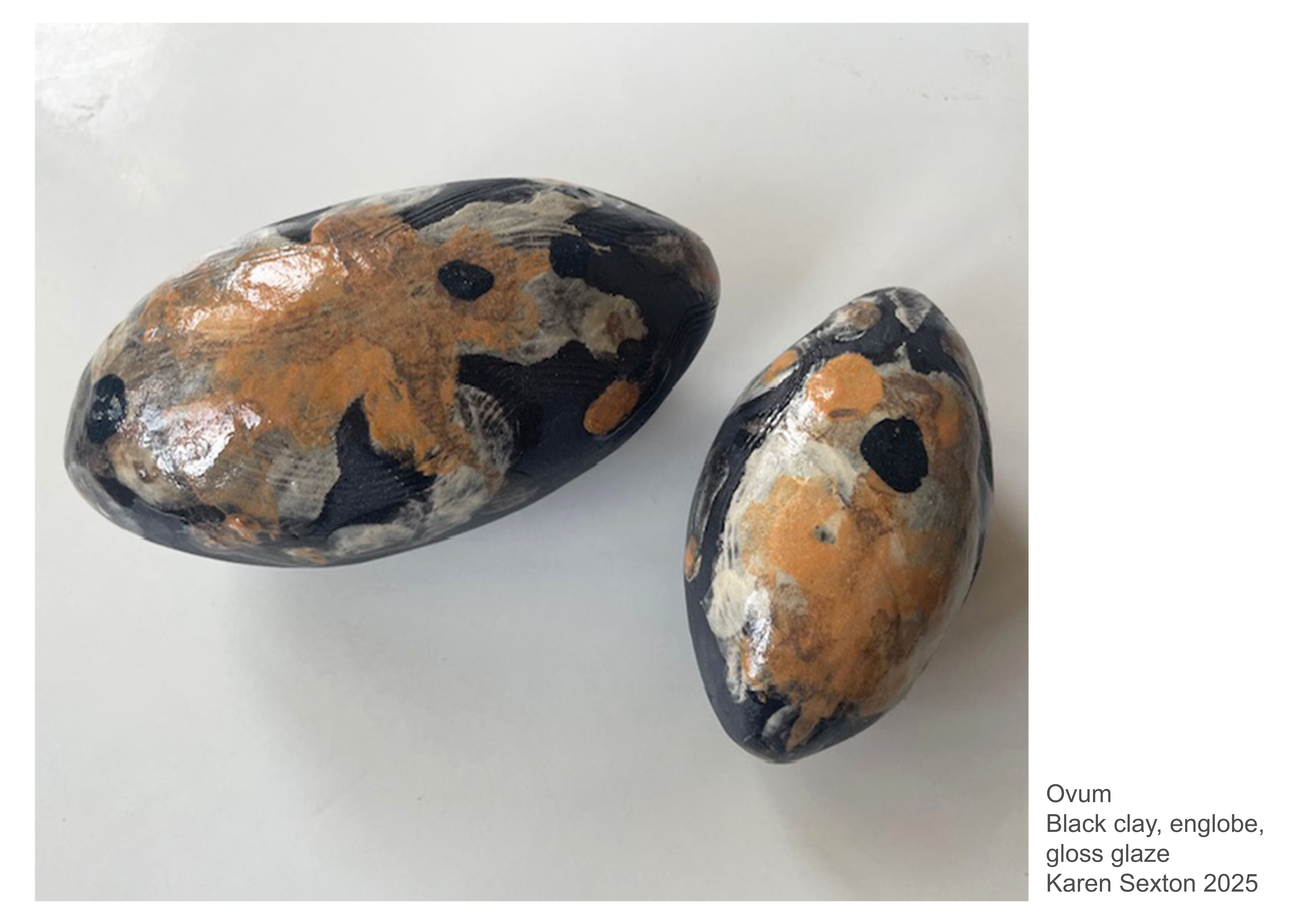 Two egg-like shapes with abstract patterning in black, silver and orange.
