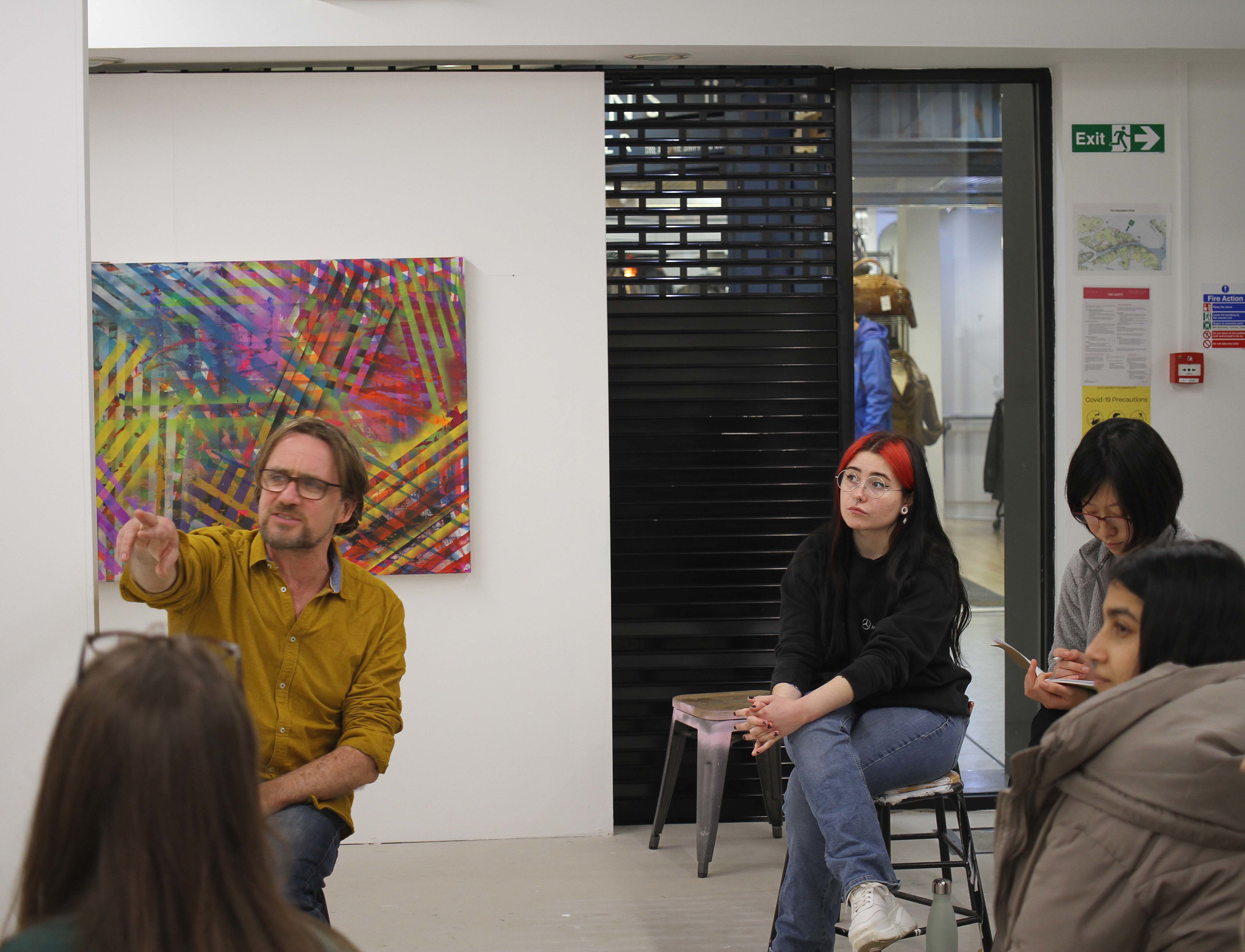 Staff and students sat looking and discussing a piece of painted artwork