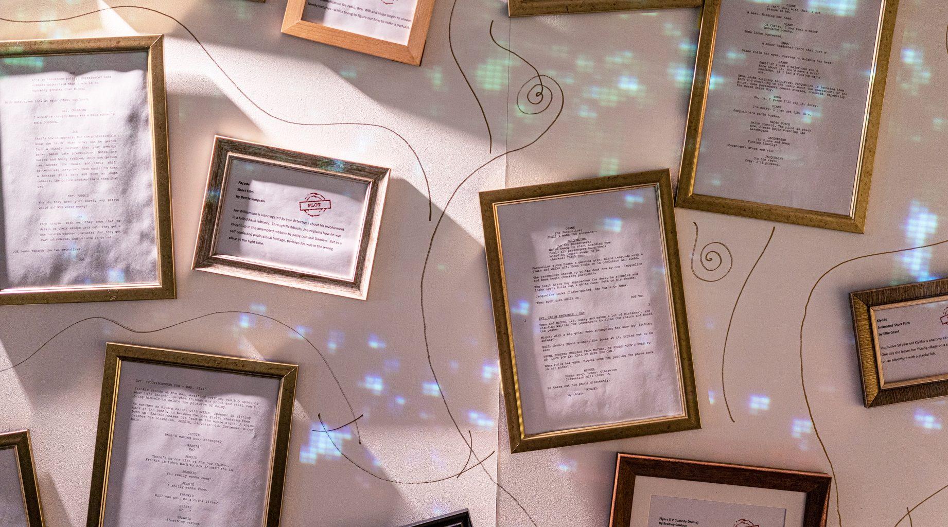 Letters and screenplay pages in frames and hanging on a wall.