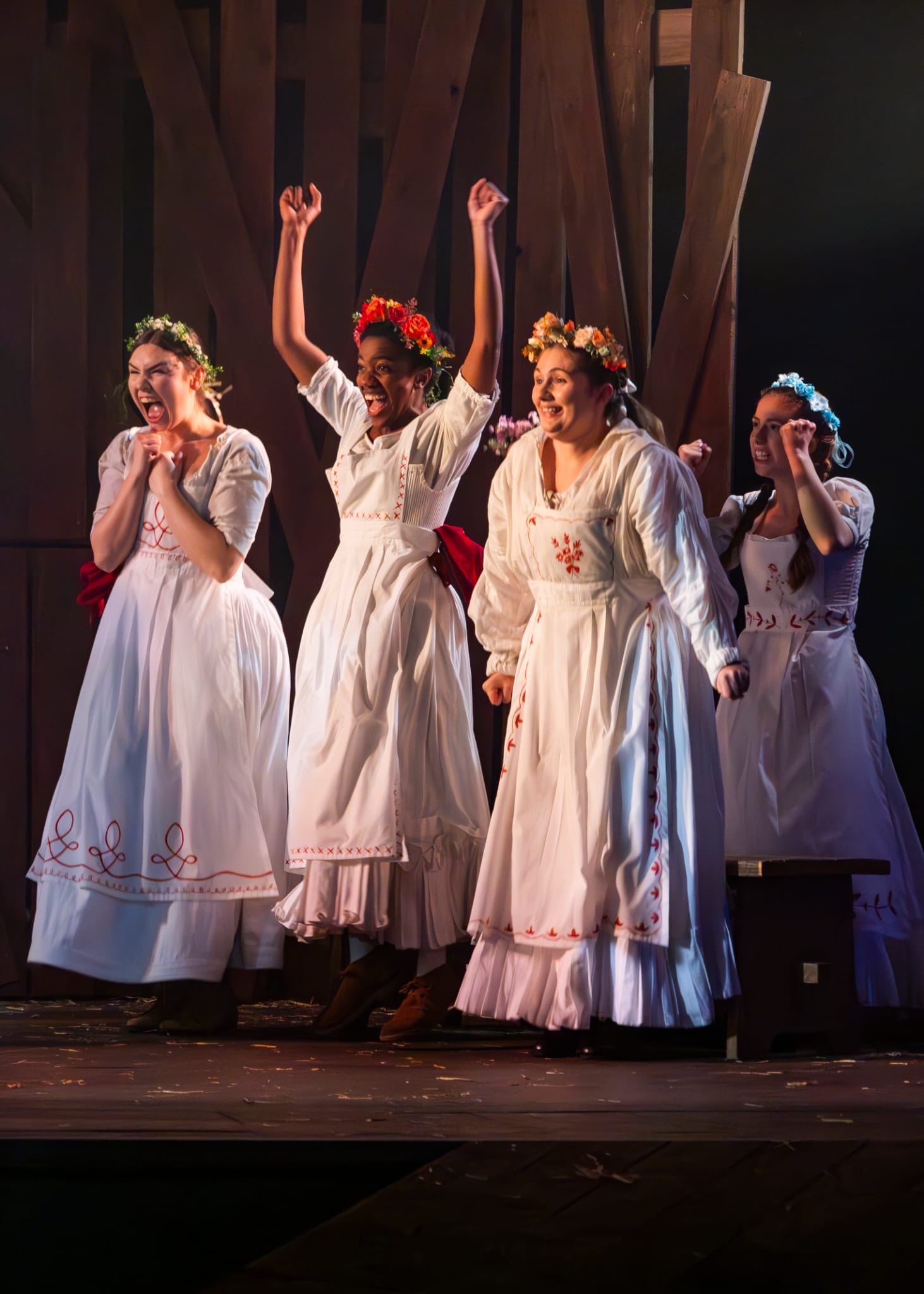 Nicole Elizabeth Phillip in The Ballad of Maria Marten wearing a white dress and red flowers alongside other actors.