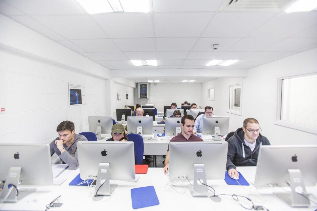 Several rows of desks and computers with students sat behind them.
