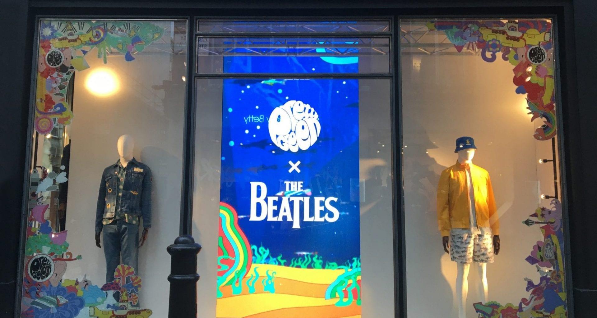 Two mannequins in Beatles-style costume. A banner hangs in the middle of the wall with bright coloured artwork and the words 'The Beatles' in the centre.